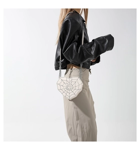 Detalle de bolso bandolera blanco en forma de corazón con patrón de telaraña negra
