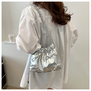Sac seau argenté métallisé avec nœuds décoratifs et bandoulière chaîne sur modèle