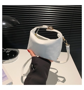 Vue détaillée du sac croissant blanc à texture ondulée avec ferrures dorées et bandoulière