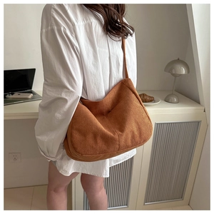 Detail showing the brown corduroy tote bag texture and its casual half-moon shape