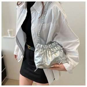 Détail du sac seau plissé argenté avec nœuds métalliques et bandoulière chaîne