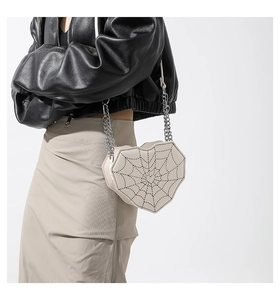 Detalle de bolso bandolera en forma de corazón con costuras de telaraña gótica y cadena