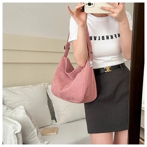 Detail of pink corduroy hobo bag with adjustable strap and cute cartoon pendant accessory