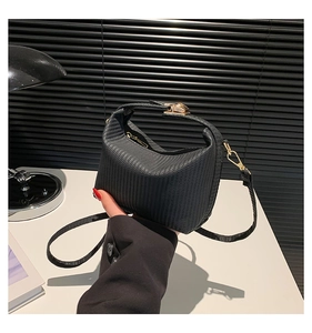 Détail d'un sac à main noir texturé avec fermoir doré et bandoulière amovible