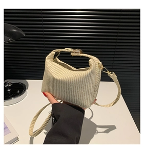 Détail d'un mini sac à main tissé beige avec fermoir métallique et bandoulière