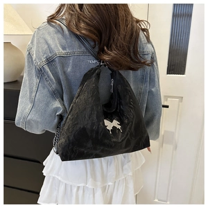 Close-up of black pleated leather hobo bag with a silver metal butterfly charm