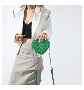 Detalle de bolso corazón verde con cadena y bordado de telaraña blanca y dije corazón