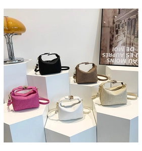 Cinq sacs à main carrés texturés en diverses couleurs sur des socles géométriques chic