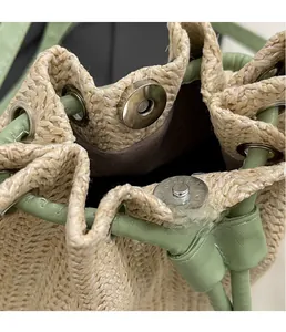 Detail of woven straw bucket bag featuring green leather trim and silver magnetic closure