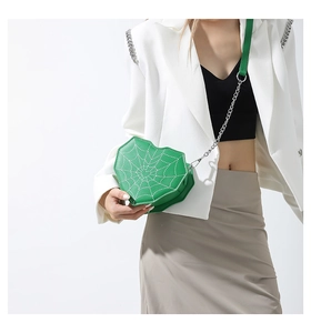 Primer plano del bolso verde corazón con costuras de telaraña blanca y cadena plateada