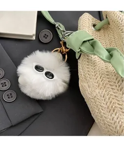 Close-up of a white plush fuzzy charm with sunglasses on a woven straw bucket bag