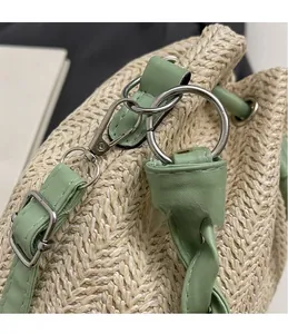 Detail of silver hardware hooks and straw weaving texture on a green bucket bag