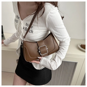 Detail of brown faux leather shoulder bag featuring a large silver square metal buckle
