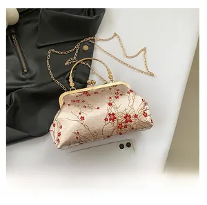 Detailed embroidery of red plum blossoms on champagne satin shell-shaped evening bag