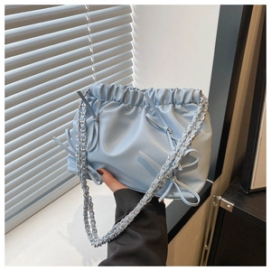 Détail du sac seau bleu clair présentant une texture plissée douce et des nœuds élégants