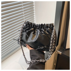 Détail du sac seau noir plissé avec petits nœuds et bandoulière en chaîne argentée