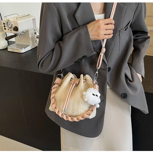 Close-up of straw bucket bag with pink leather drawstring and cute plush pendant