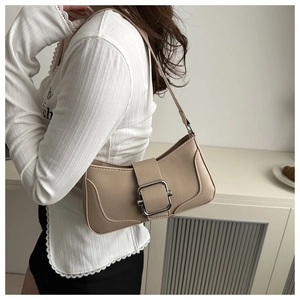 Detail shot of a beige shoulder bag with a large silver square metal buckle on leather