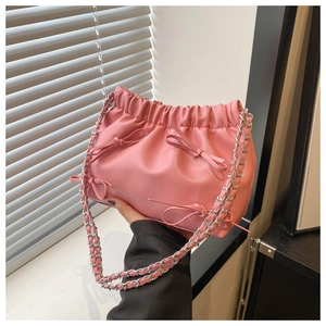 Détail du sac bandoulière rose avec nœuds et bandoulière en chaîne argentée