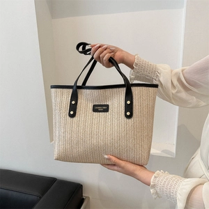 Large beige woven straw tote bag with black leather trim and top handles for women