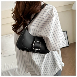 Detail view of a black leather shoulder bag with a large silver square metal buckle