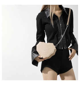Detalle de bolso bandolera beige con forma de corazón y bordado de telaraña blanca