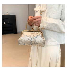 Detail of vintage Chinese style satin handbag with blue floral embroidery and gold handle