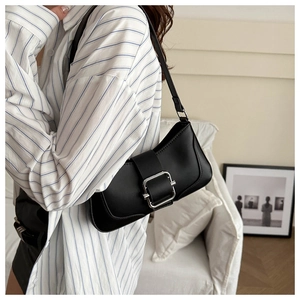 Detail of black leather underarm bag with silver square buckle worn with a casual outfit