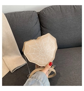 Vista detallada del bolso beige en forma de corazón con patrón de telaraña y cadena