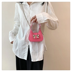 Détail du sac à main rose demi-lune avec nœud argenté et fine bandoulière chaîne