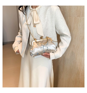 Close-up of floral embroidery on beige satin clutch with gold handle and chain