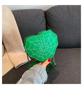 Detalle del bolso de hombro verde en forma de corazón con costuras de tela de araña blanca