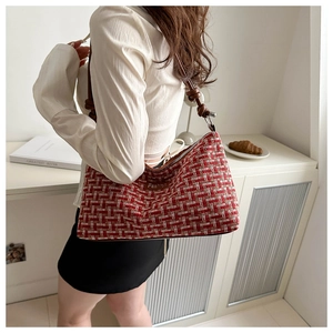 Detail of red and white plaid tweed shoulder bag with decorative brown leather knot strap