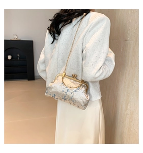 Model wearing a vintage shell-shaped crossbody bag with floral jacquard and chain strap