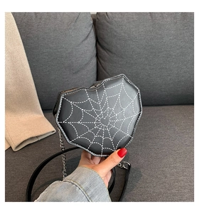 Detalle de bolso bandolera con forma de corazón, costuras de telaraña blanca y cadena