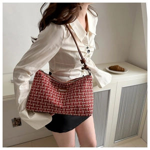Detail der rot-weißen Tweed-Schultertasche mit Lederriemen und Mode-Etikett