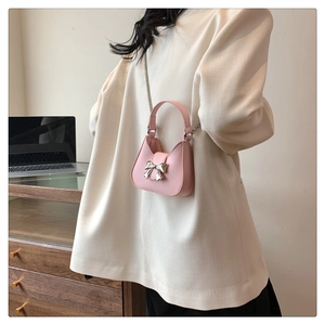 Détail du mini sac rose avec boucle nœud argentée et bandoulière chaîne sur tenue décontractée