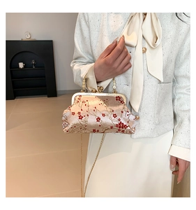 Detail of champagne satin handbag with red plum blossom embroidery and metal chain