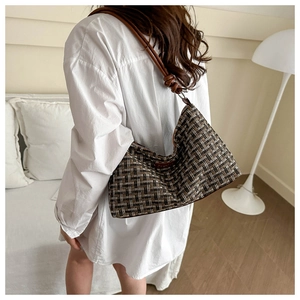 Detail der Tweed-Hobo-Tasche mit Vintage-Karo und Lederriemen an der Schulter getragen