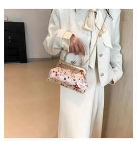 Detail of red plum embroidery on champagne satin handbag with heart clasp and gold chain