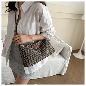 Detail der gewebten Tweed-Umhängetasche mit Vintage-Karomuster und Fashion-Lederetikett