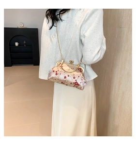 Detail of champagne satin bag with red plum blossom embroidery and gold chain handle