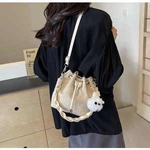 Detail of woven straw bucket bag with drawstring closure and plush lamb charm