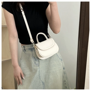 Mirror selfie showing the white leather saddle bag with top handle and gold hardware