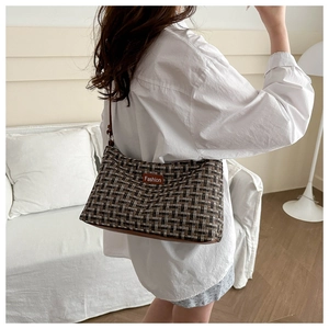 Detailansicht der braunen karierten Tweed-Schultertasche, getragen von einem Modell