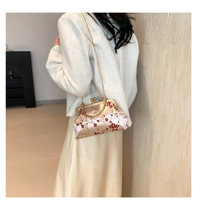 Detail of embroidered floral shell bag with golden metal chain and vintage top handle