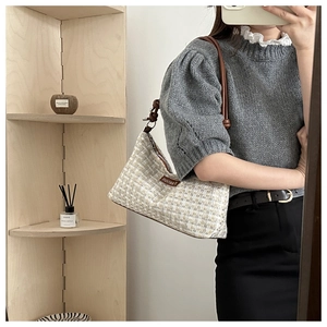 Detail der gewebten Tweed-Hobo-Tasche mit dunkelbraunem Lederknotenriemen und Etikett