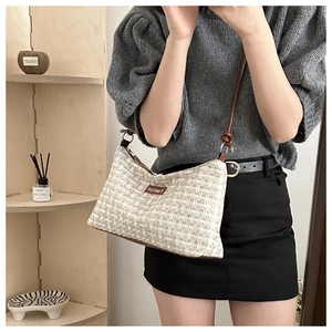Detail showing beige woven texture shoulder bag with leather fashion label and slim strap