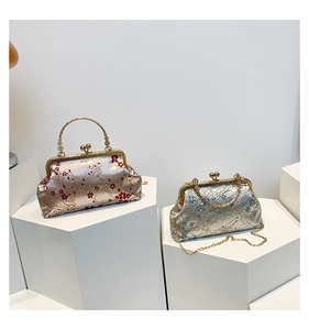 Detail of floral embroidery on retro shell bags with metal handles and gold chain straps