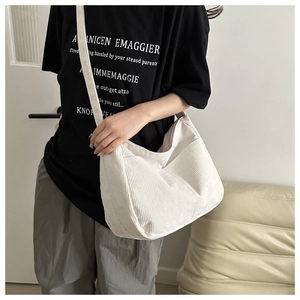 Close-up of white corduroy dumpling bag with wide strap on model for daily casual wear
